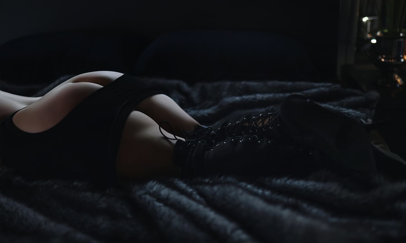 A dark and moody close-up of a person's hand resting on a textured black surface.