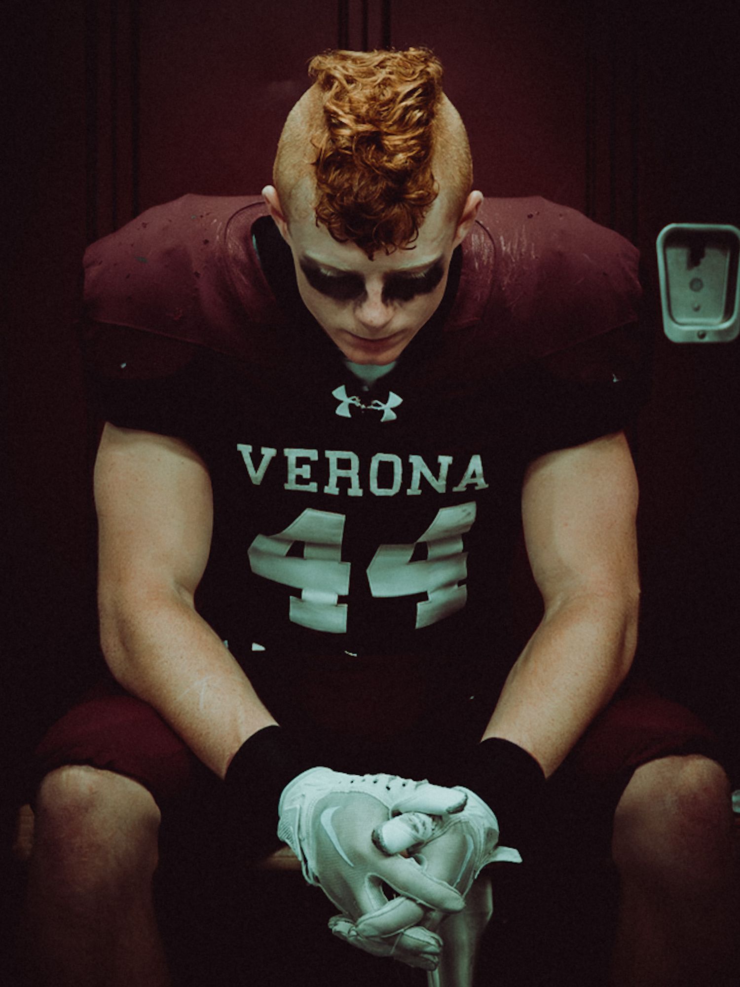 A young football player in a maroon Verona jersey drinks from a large stainless steel water jug.