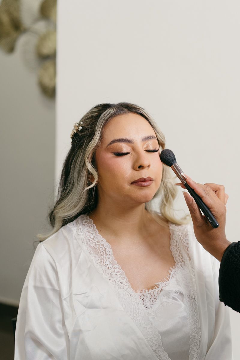 Close-up shots of makeup application process on someone wearing a white lace-trimmed robe.