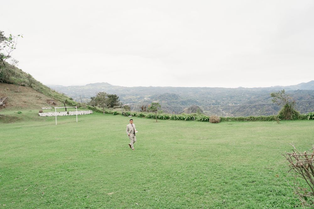 Rolling green hills and mountains create a scenic pastoral landscape under a bright cloudy sky.
