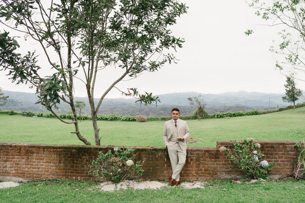 A scenic outdoor wedding venue with brick walls, green grass, and trees against a mountain backdrop.