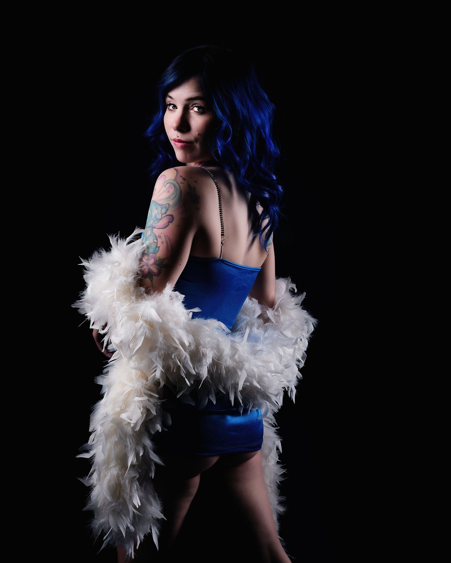 David G Holt Photography - Figure wearing white feather boa and blue outfit against black background in glamour portrait.