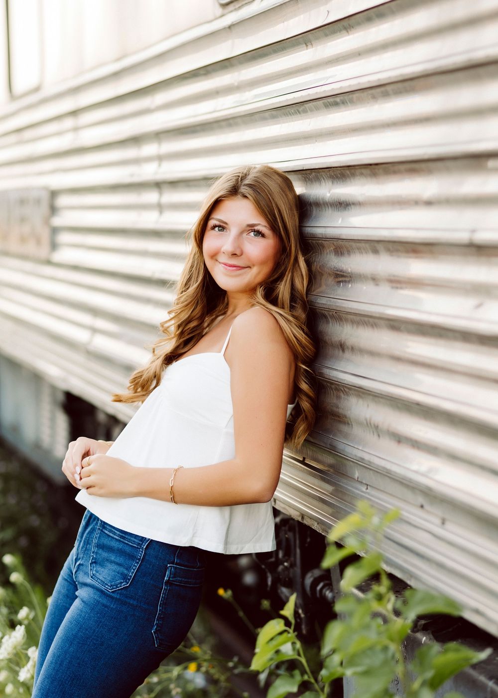 Casual portrait against white siding wall wearing white top and jeans.