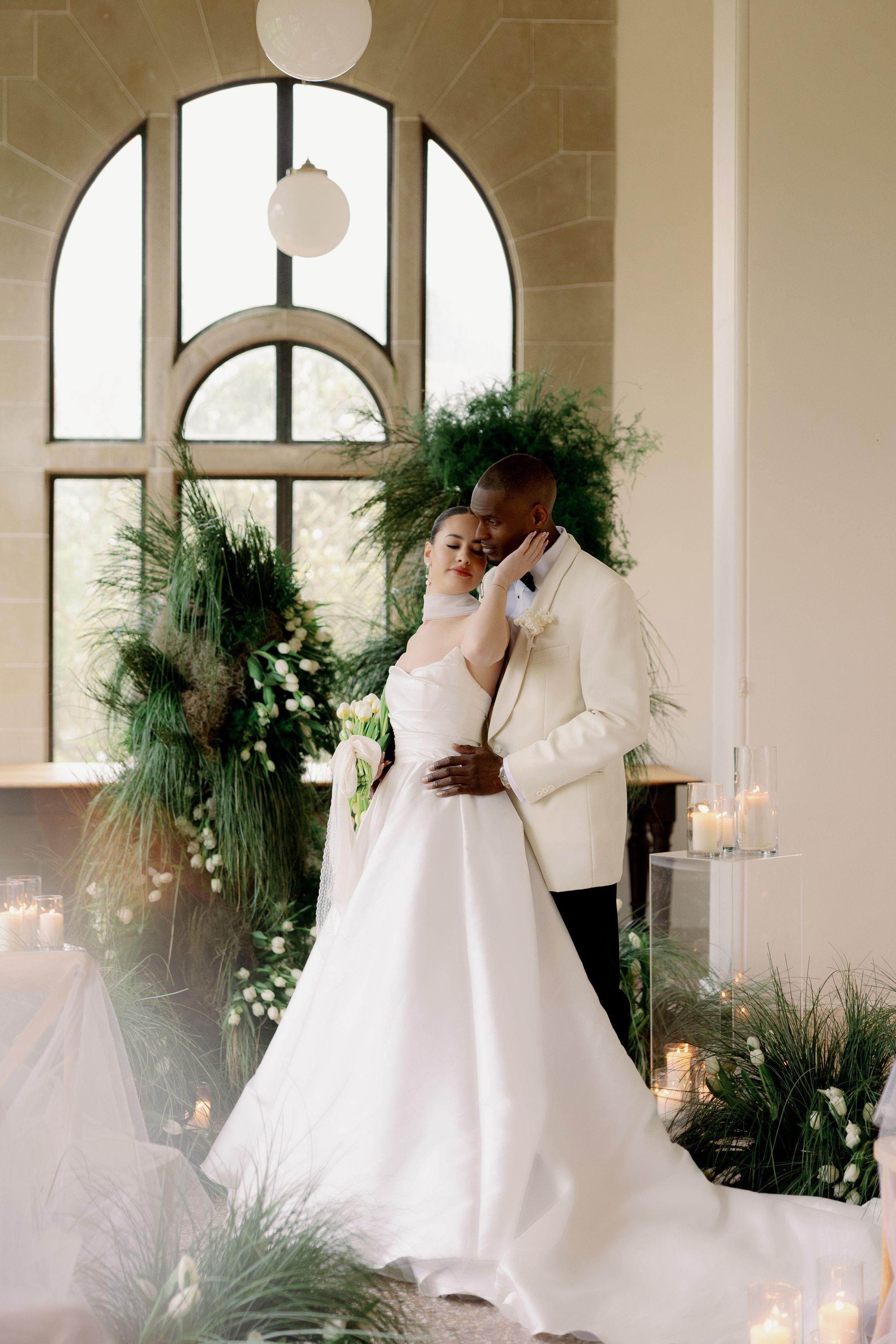 A series of romantic wedding photos showing a couple in white attire embracing in an elegant venue with arched windows.