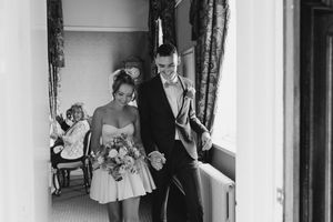 Black and white photograph showing a bride and bridesmaids preparing in a bridal suite before the wedding ceremony.