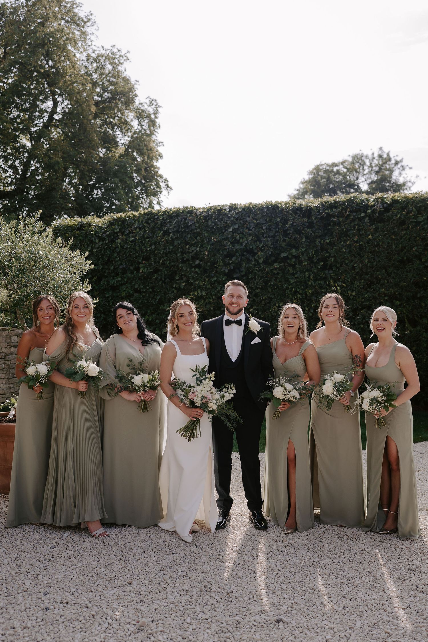 bride and groom and bridesmaids smiling for a portrait at ivy lodge in cirencester