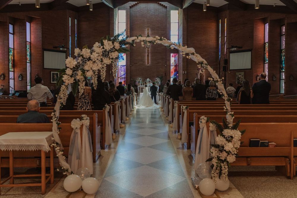Elegant church wedding aisle with white floral arch and balloon decor leading to altar.
