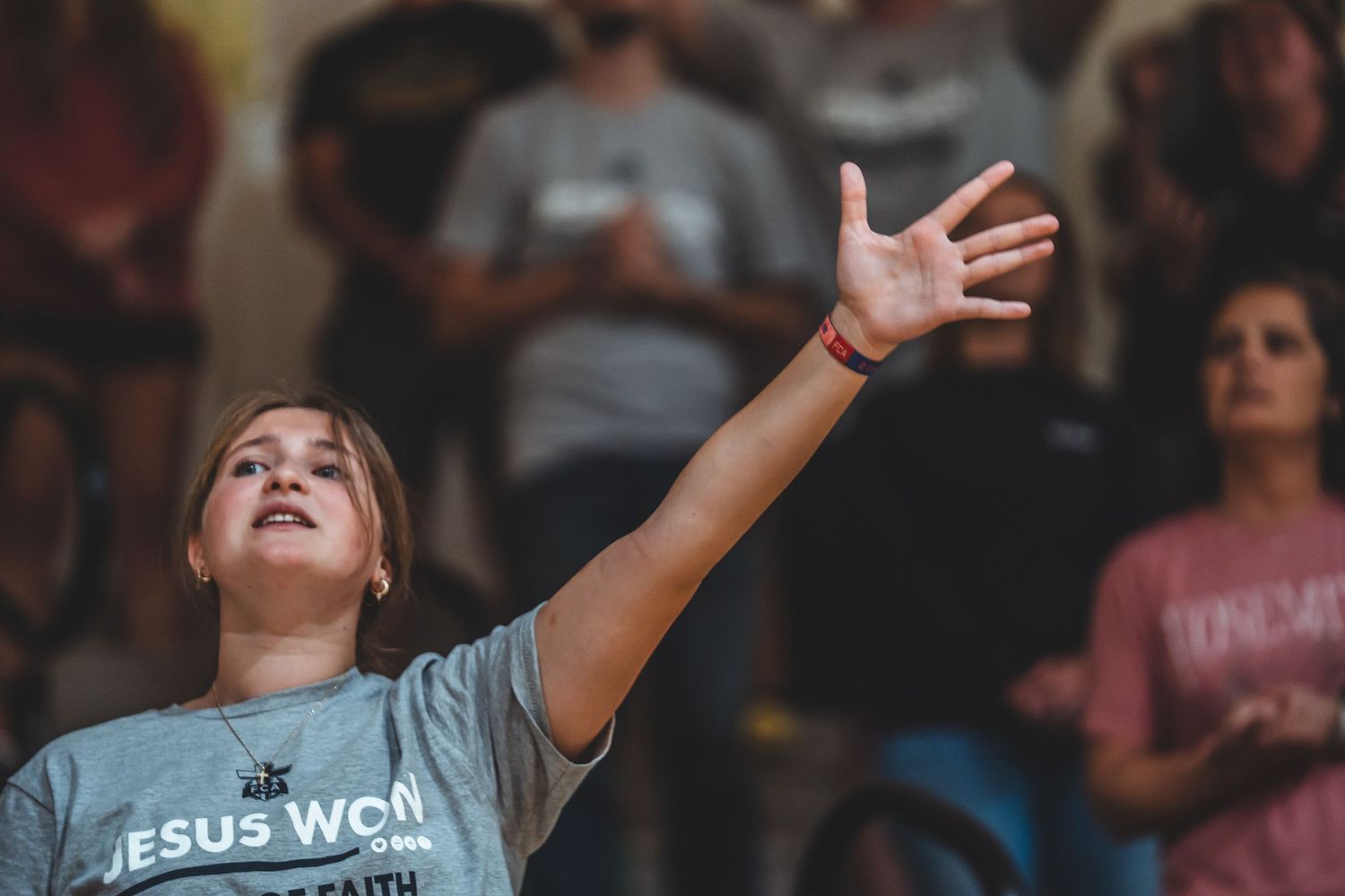 A group of people raise their hands in worship during a Christian church service.