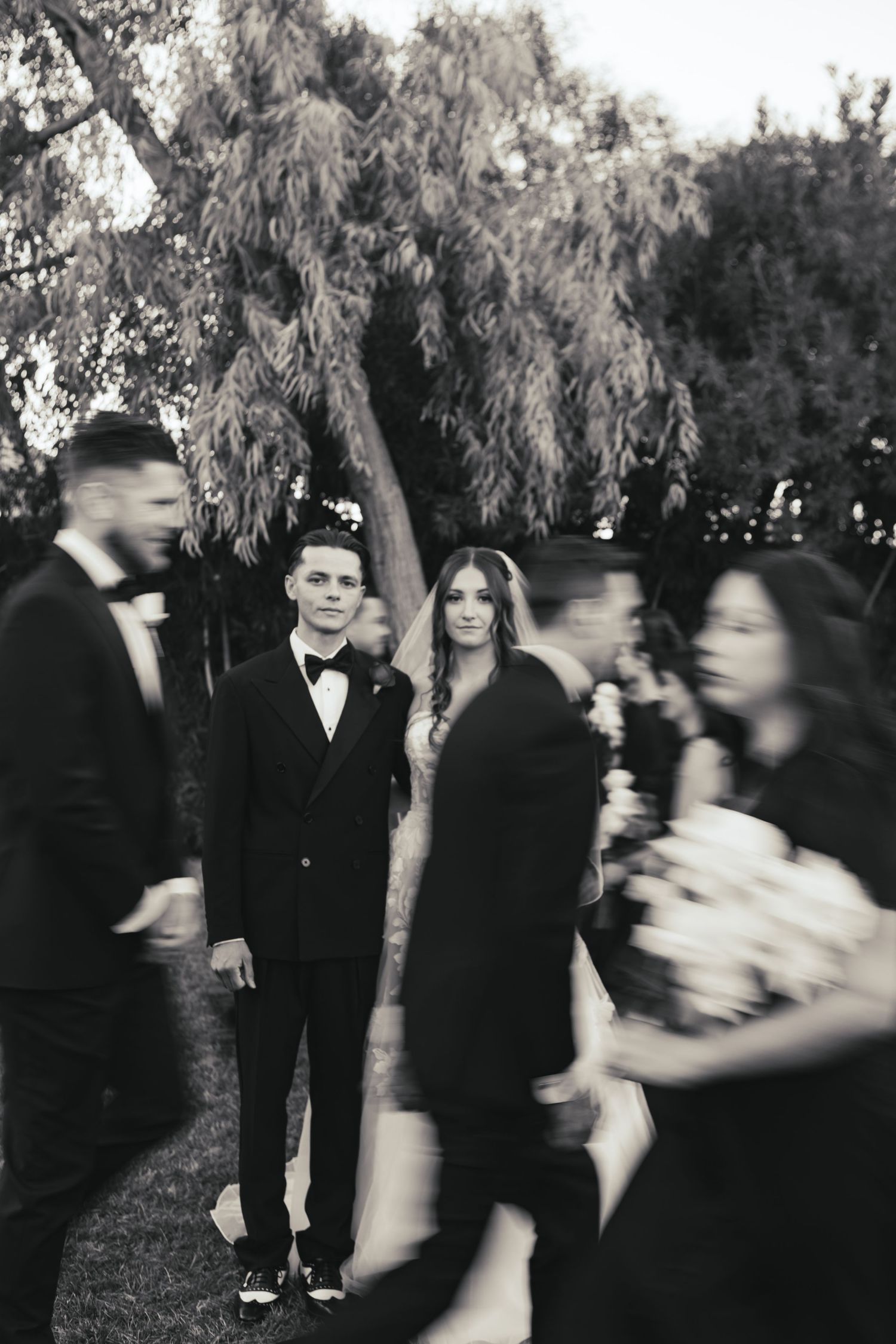 Bride and groom while the wedding party passes by during their luxury wedding.