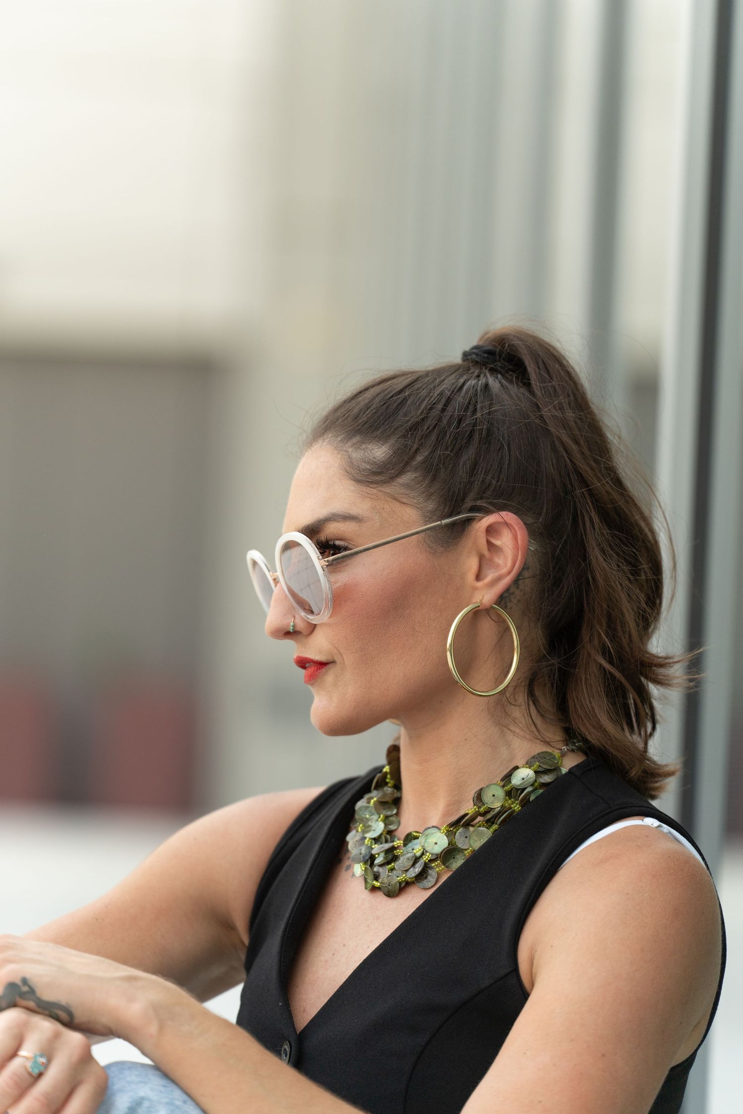 A person in a black sleeveless top and glasses poses in a sequence of four expressive profile shots.