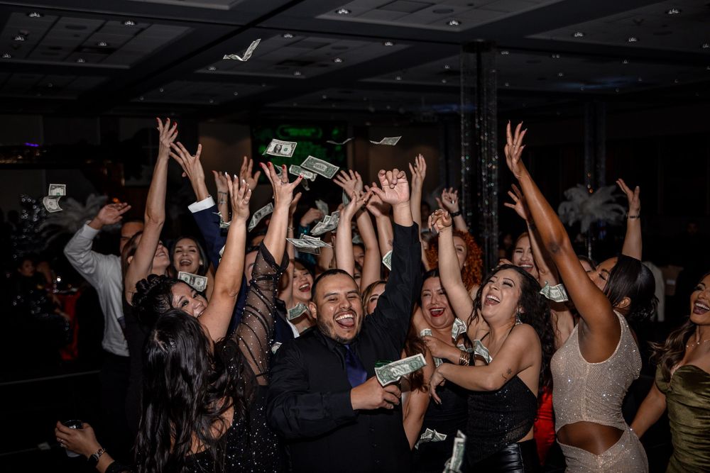 Crowd of people dancing with raised arms at a nightclub party under dark lighting.