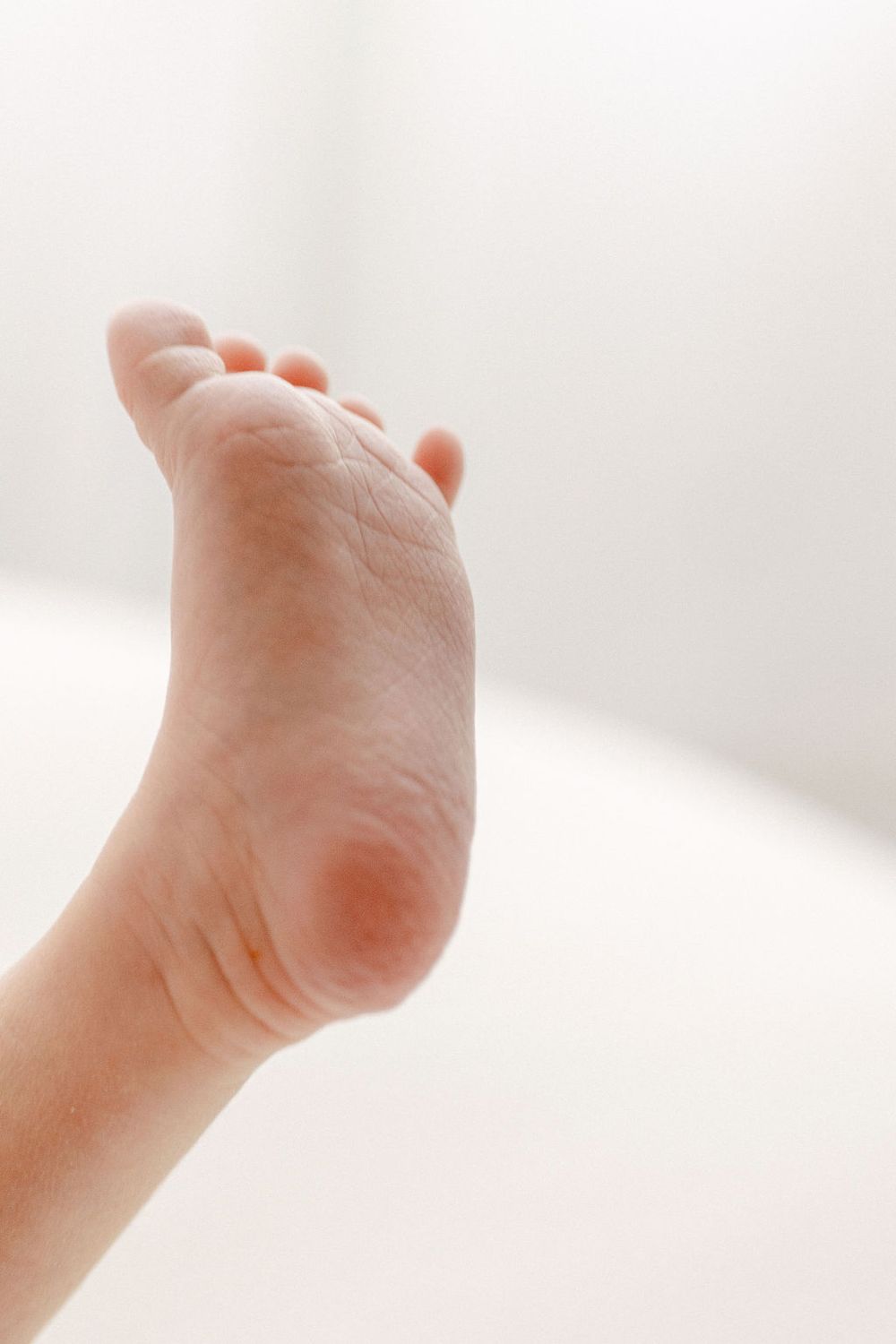 Close-up view of tiny baby foot showing delicate skin and toes against white background. Connecticut Newborn Photography.