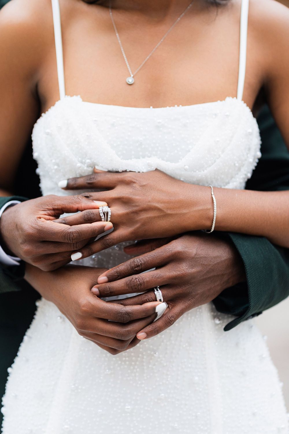 Close-up shots of interracial couple's hands with wedding rings, showing bride in white dress and groom's darker skin.