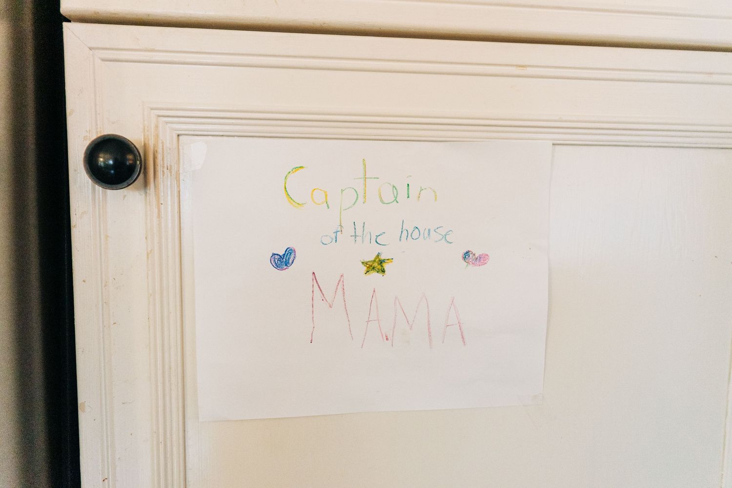 A white door with children's artwork and colorful drawings posted on it.