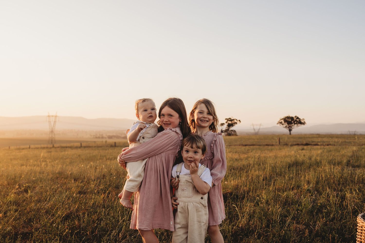 A group of people stand together in a golden field at sunset creating a warm and joyful outdoor portrait.