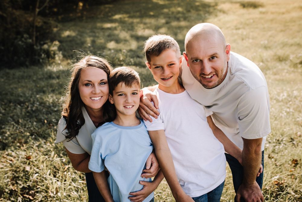 Family enjoying quality time together outdoors on a sunny day in a grassy field.