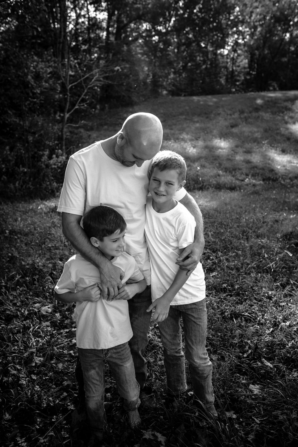 Two people share a playful and affectionate moment together outdoors in a black and white photograph.