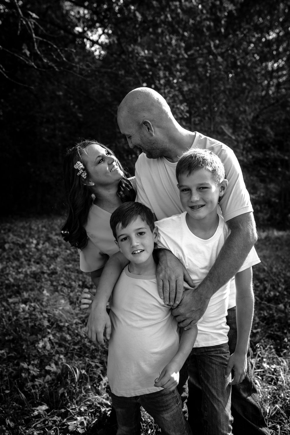 Black and white photos of playful parent-child moments outdoors with natural expressions and embraces.