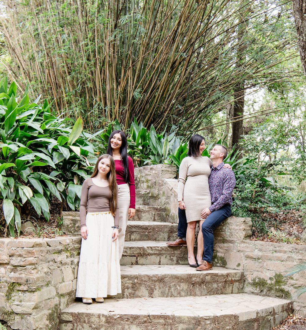 Family of four poses on stone steps surrounded by bamboo garden.