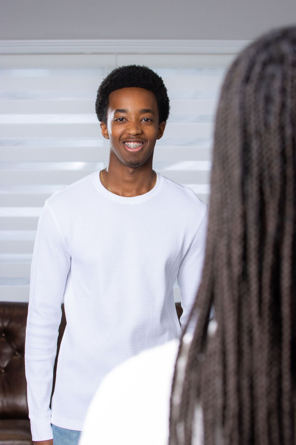 A series of photos showing someone in a white long-sleeve shirt smiling and posing against a light background.