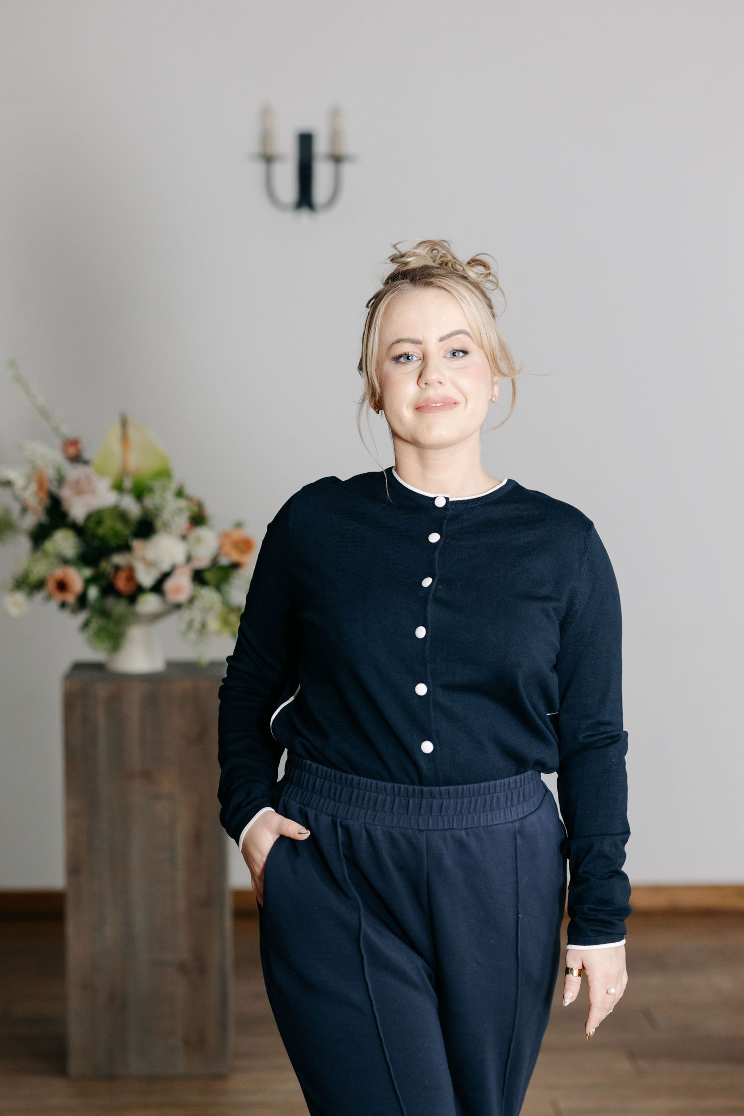 A series of photos showing a florist wearing a navy blue outfit against a light gray studio backdrop. for branding session