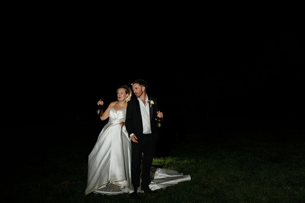 A bride and groom dance together at night on an illuminated outdoor dance floor during their wedding reception.