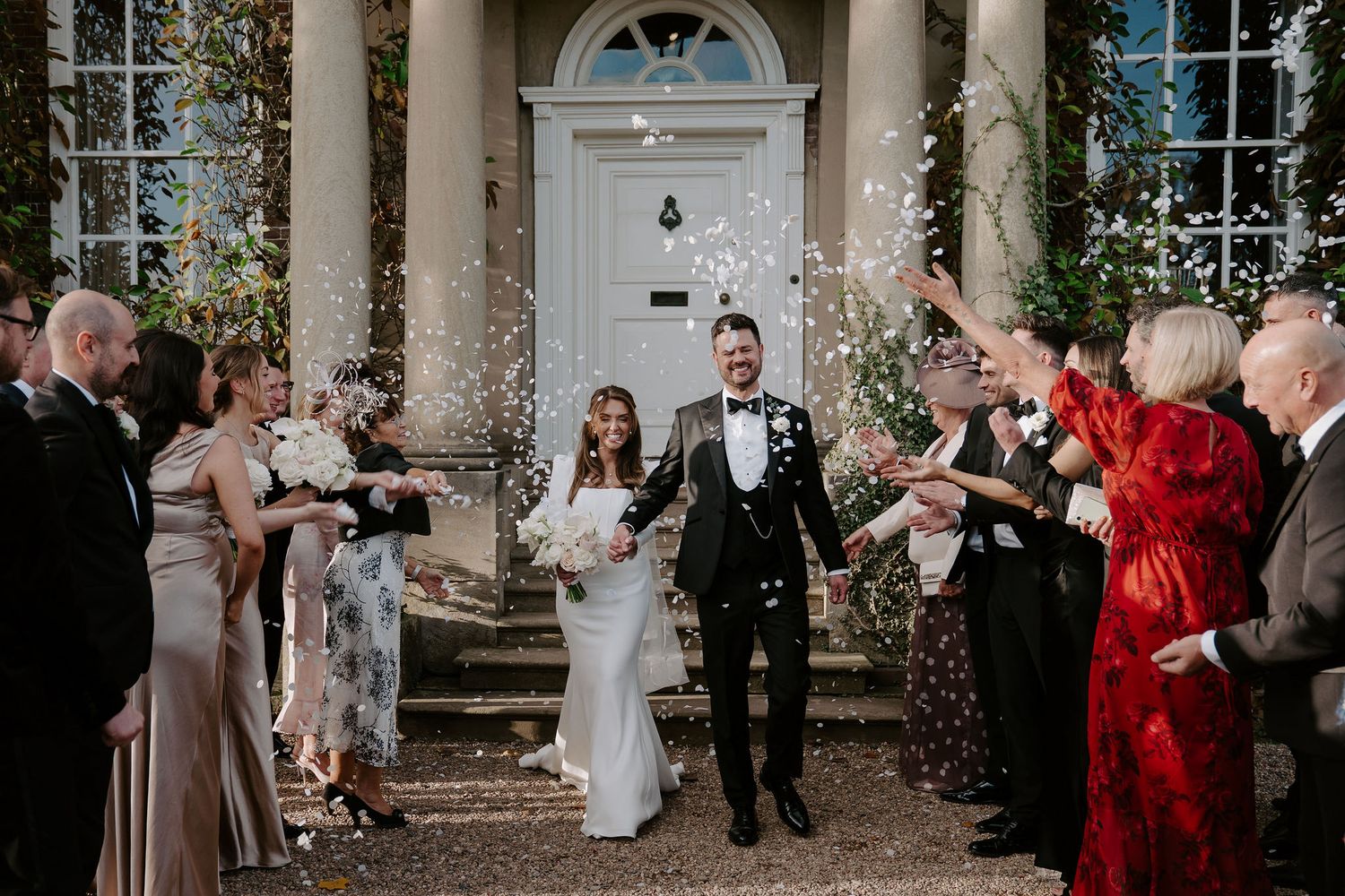 wedding guests throwing confetti over the bride and groom at Iscoyd park