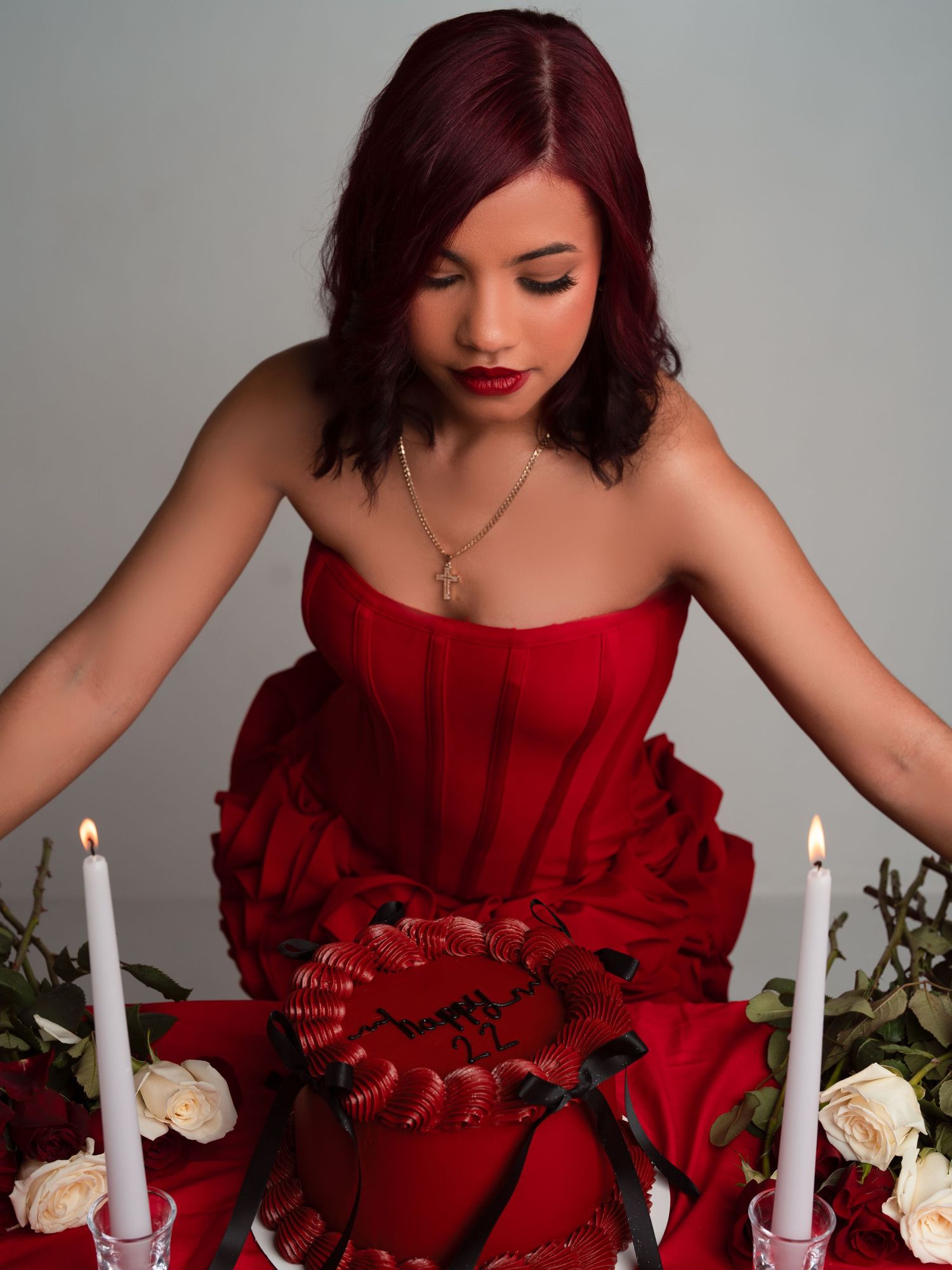 A person in a red dress arranges white candles and roses on a table in a sequence of elegant styling shots.