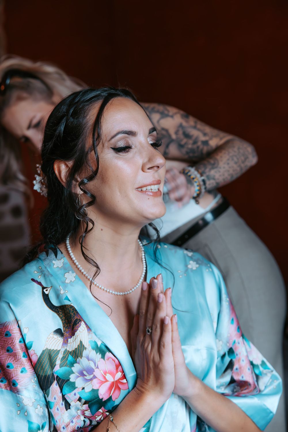 A person in a light blue floral robe with curled hair getting their makeup done in a series of sequential photos.