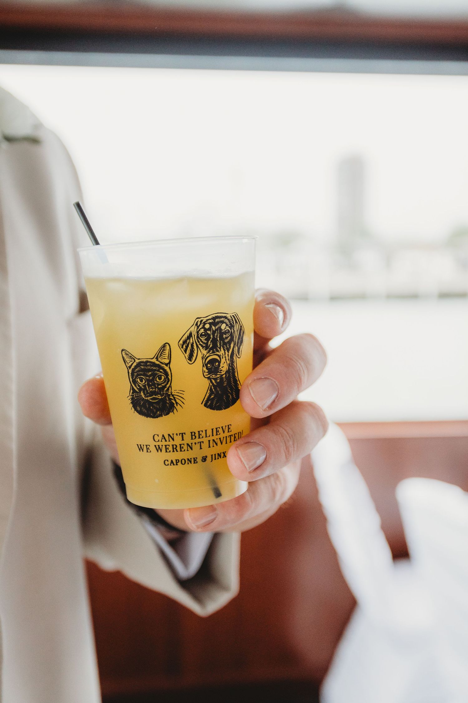 Hands holding small yellow beer tasting glasses with brewery logo at a craft beer tasting event.