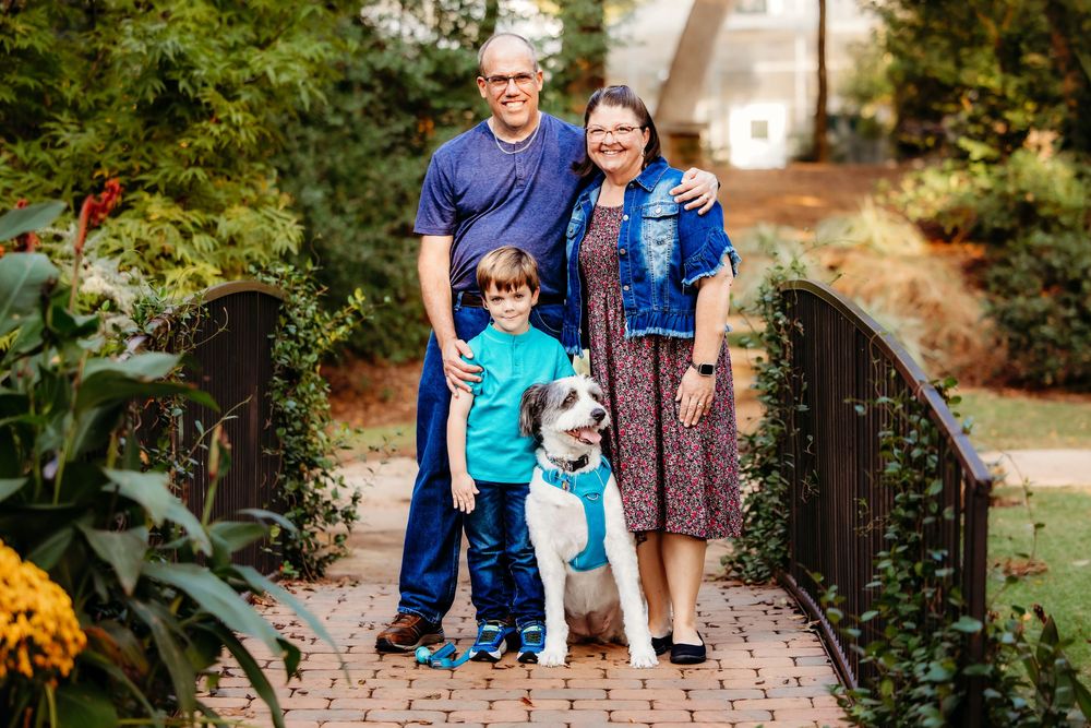 Family walking together on a stone path surrounded by lush greenery in an outdoor garden setting.