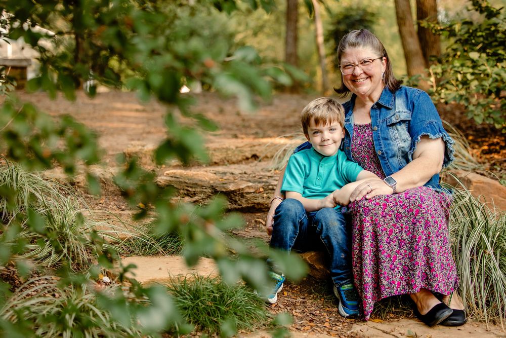 Candid outdoor family portraits in a wooded setting with natural fall foliage and warm lighting.