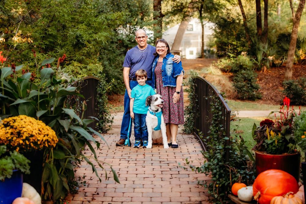 People walk through a garden path decorated with autumn pumpkins and fall foliage at a botanical garden event.