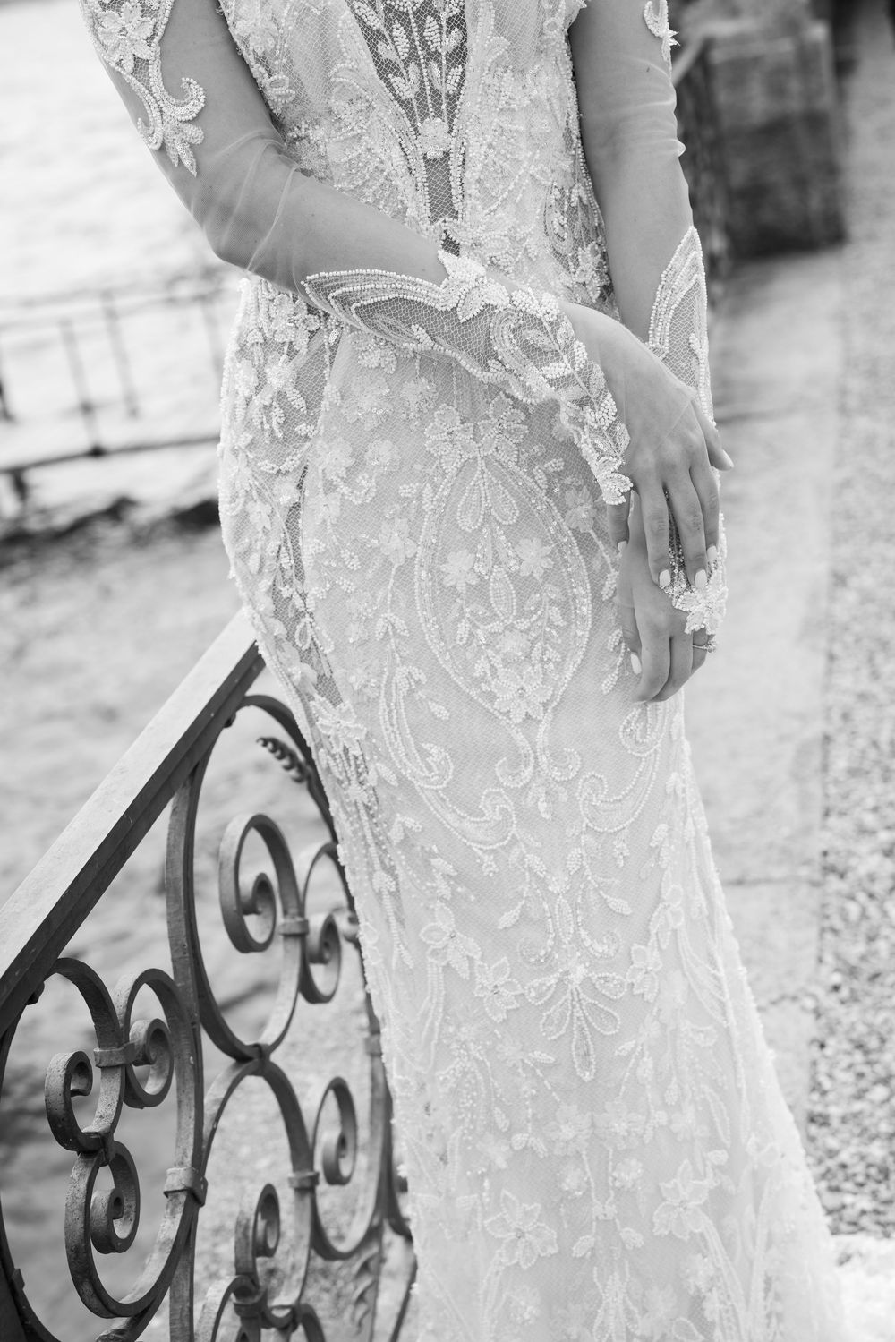 Close-up details of intricate lace patterns on a white wedding dress with decorative iron railing.