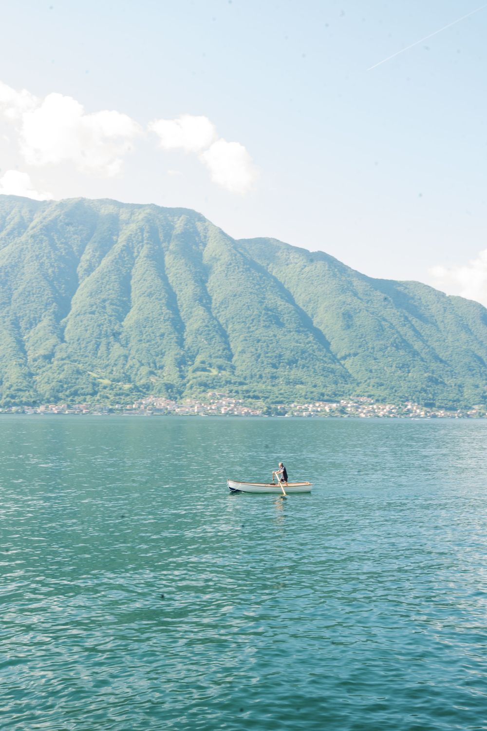 Serene mountain lake view with paddleboarder gliding across blue waters.