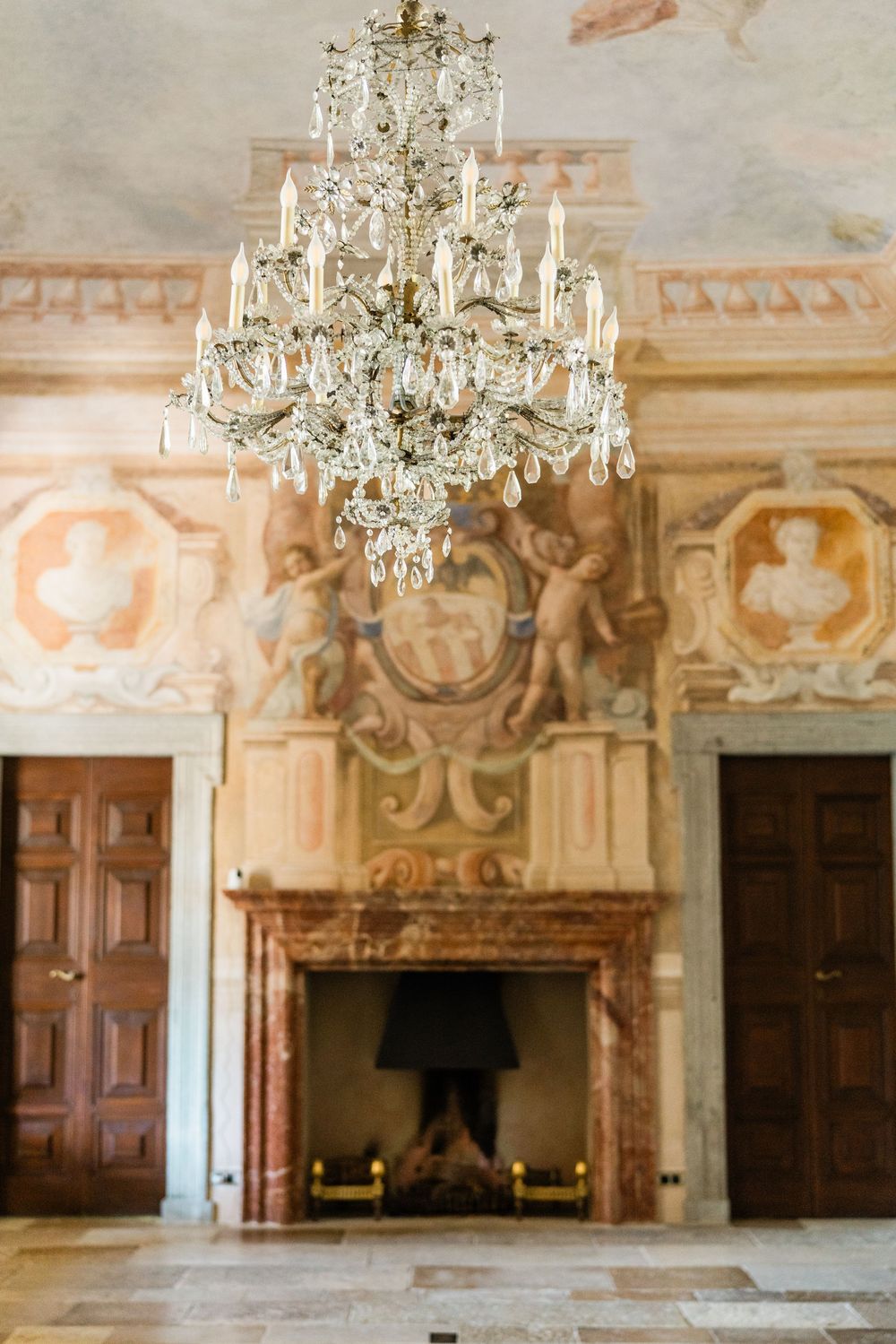 Elegant baroque room with crystal chandeliers and ornate frescoes adorning the walls and ceiling.