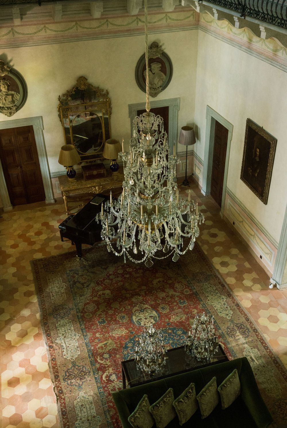 Grand ballroom with crystal chandeliers and Persian rugs viewed from above.