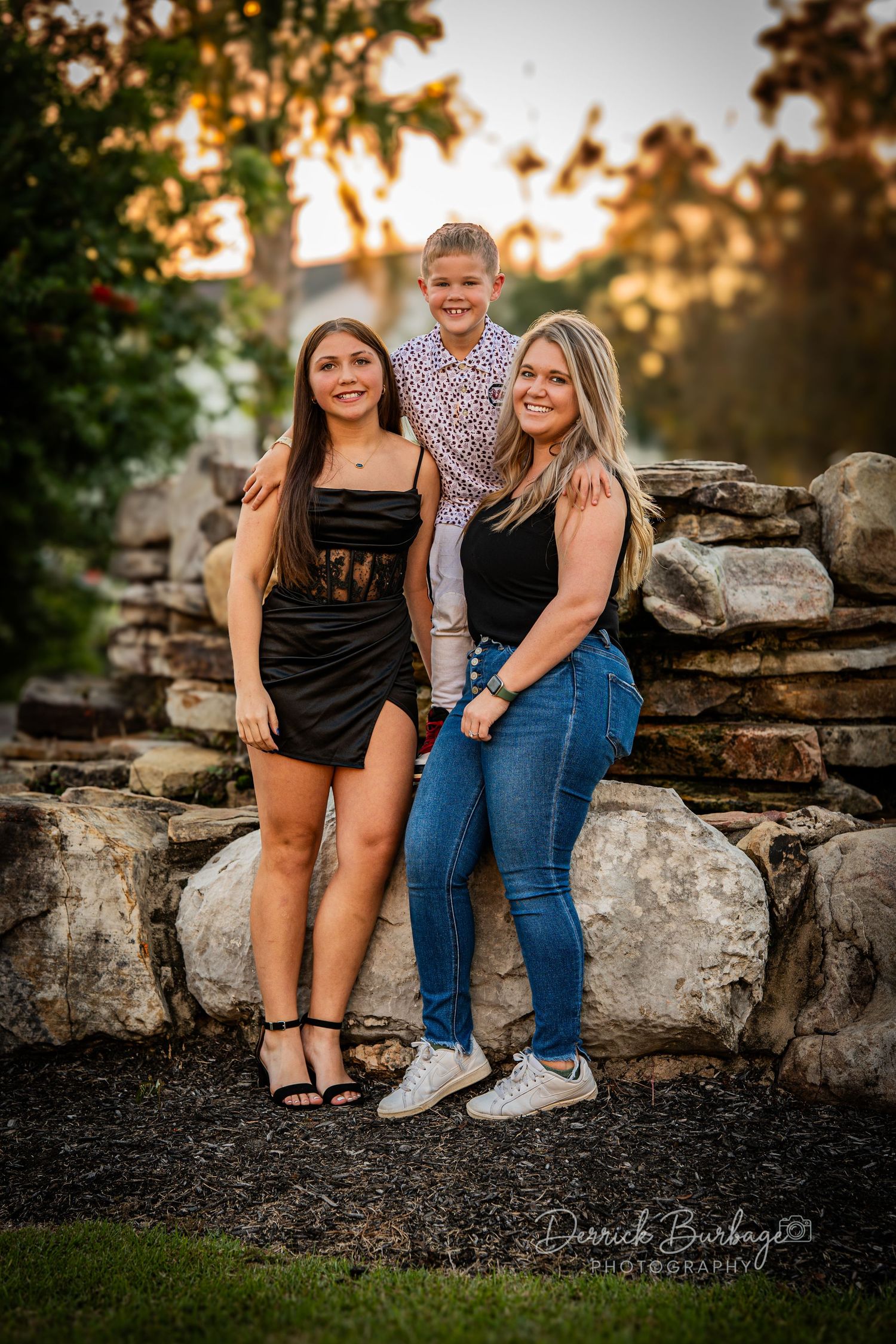 Outdoor portrait session on stone wall at sunset with natural lighting.