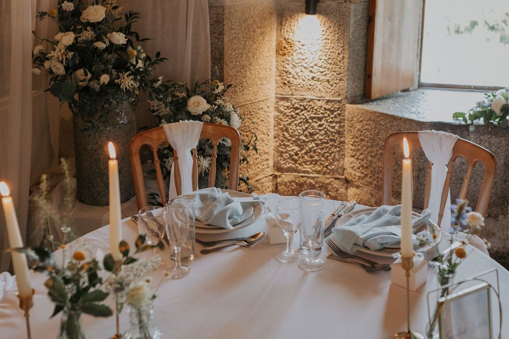 Romantic wedding table setting with white florals, tall candles, and soft blue napkins.