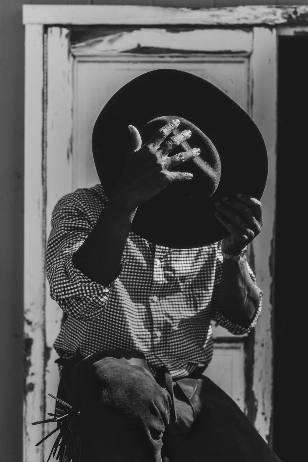 Two figures in black hats and checkered shirts stand close together in a vintage black and white photograph.