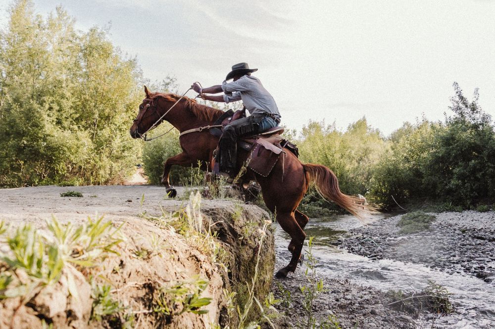 Horse and rider traversing rugged terrain along a scenic mountain trail.