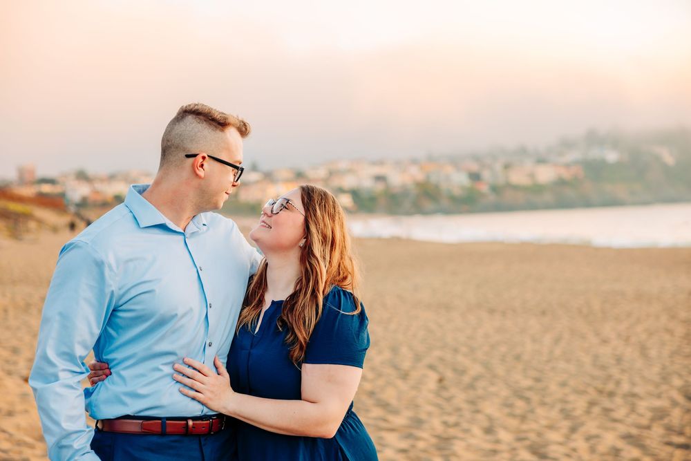 Intimate beach portrait session at sunset with soft warm lighting and sandy backdrop.
