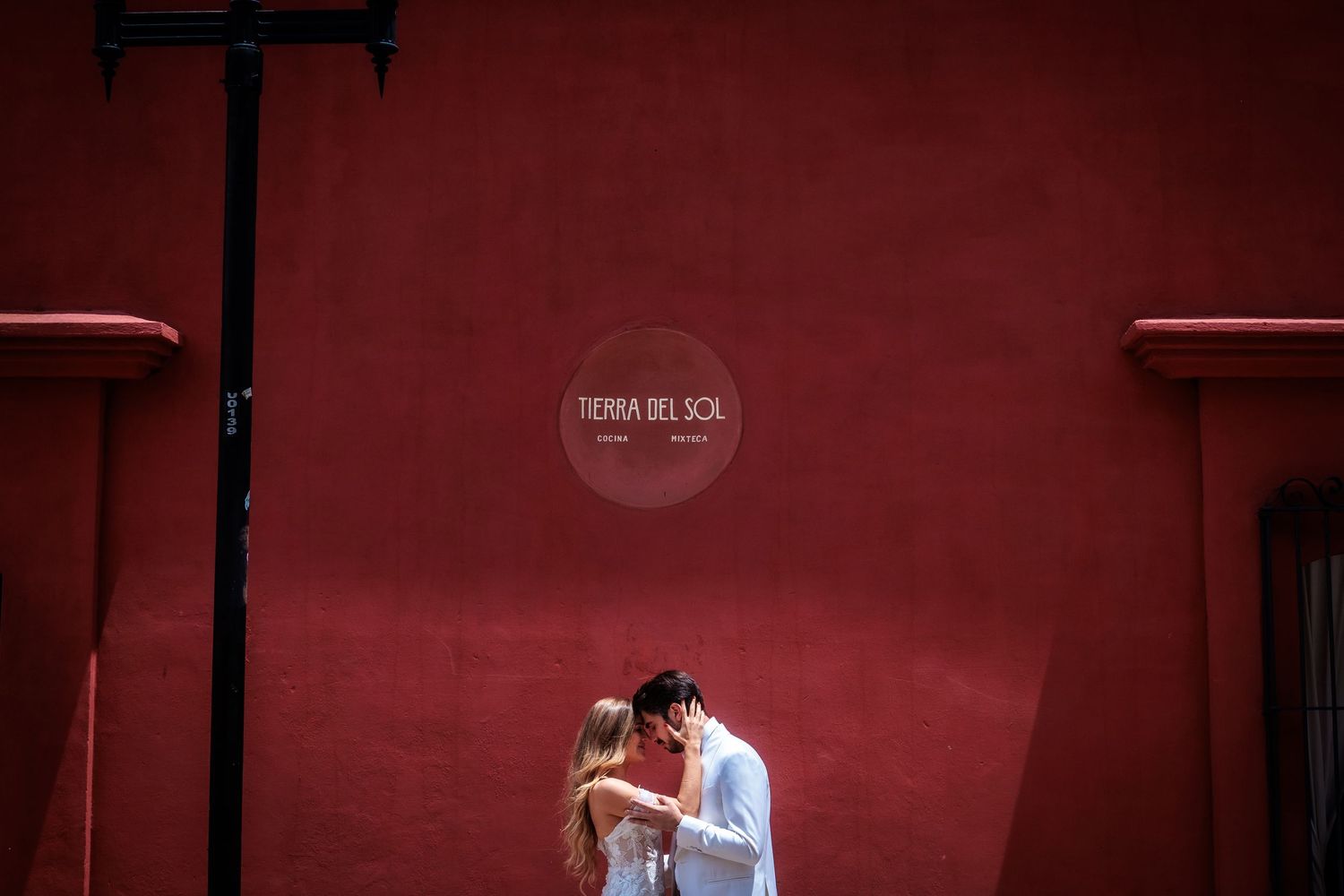 Modern portrait session against a deep red wall creating a dramatic backdrop.