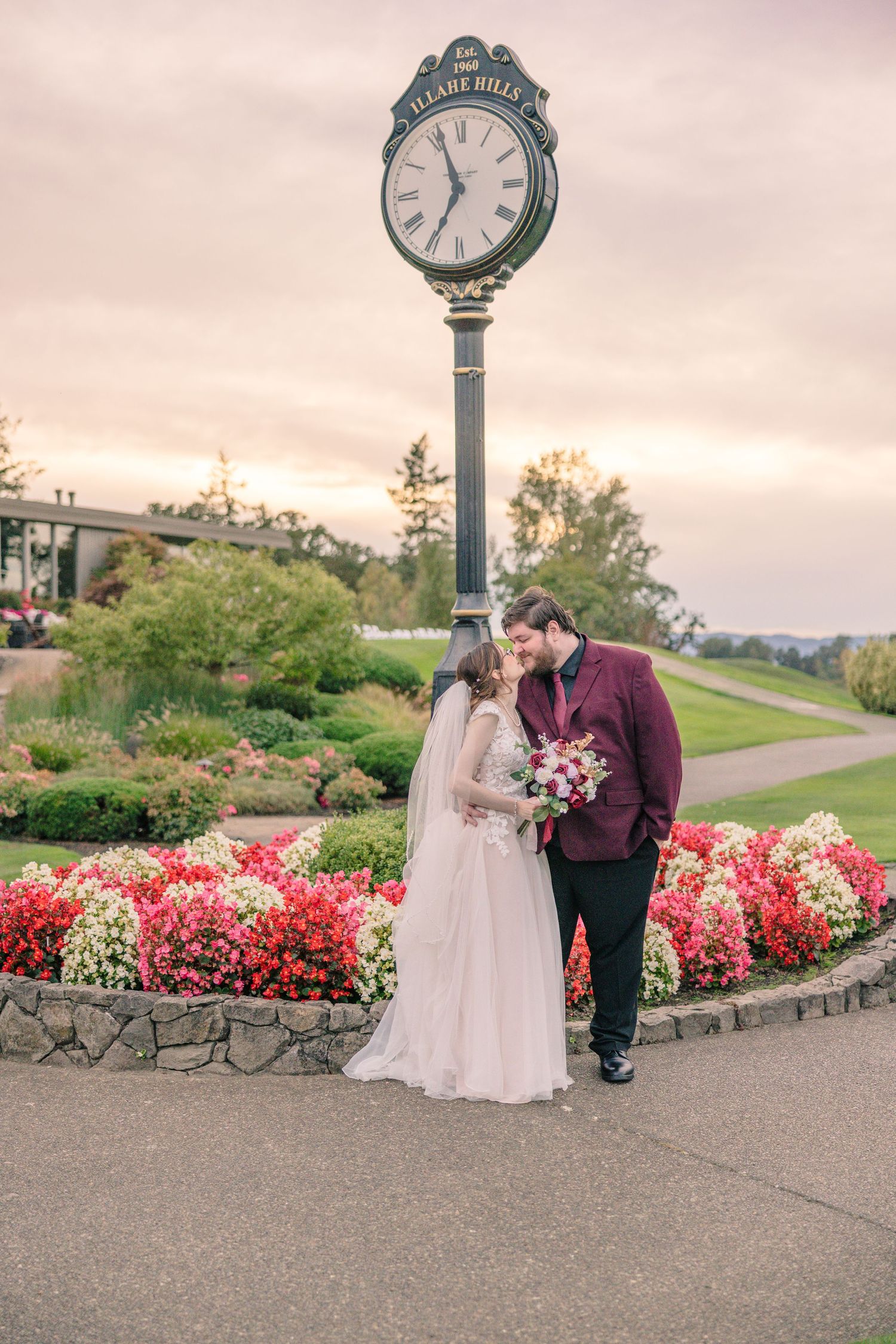 Romantic couple sharing a moment near blooming flowers and vintage clock at sunset.