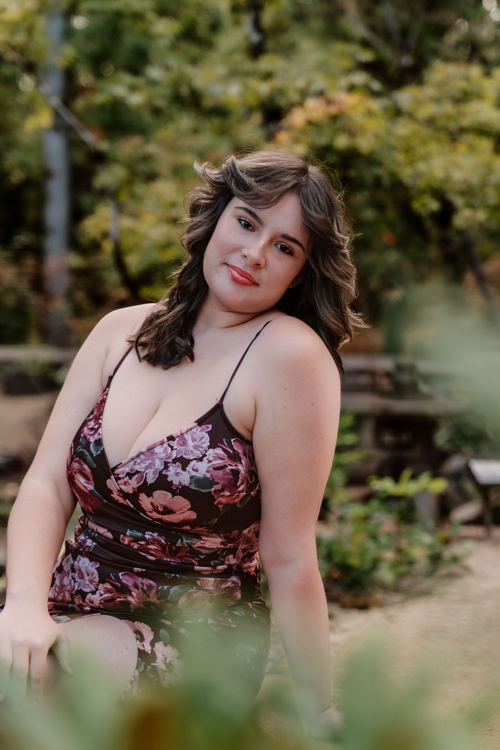 A floral dress portrait in a garden setting with natural lighting and soft bokeh background.