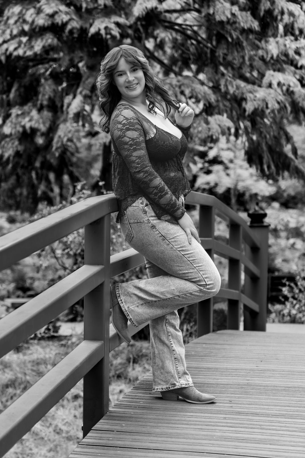 Black and white portrait on a wooden bridge with lace top and jeans.