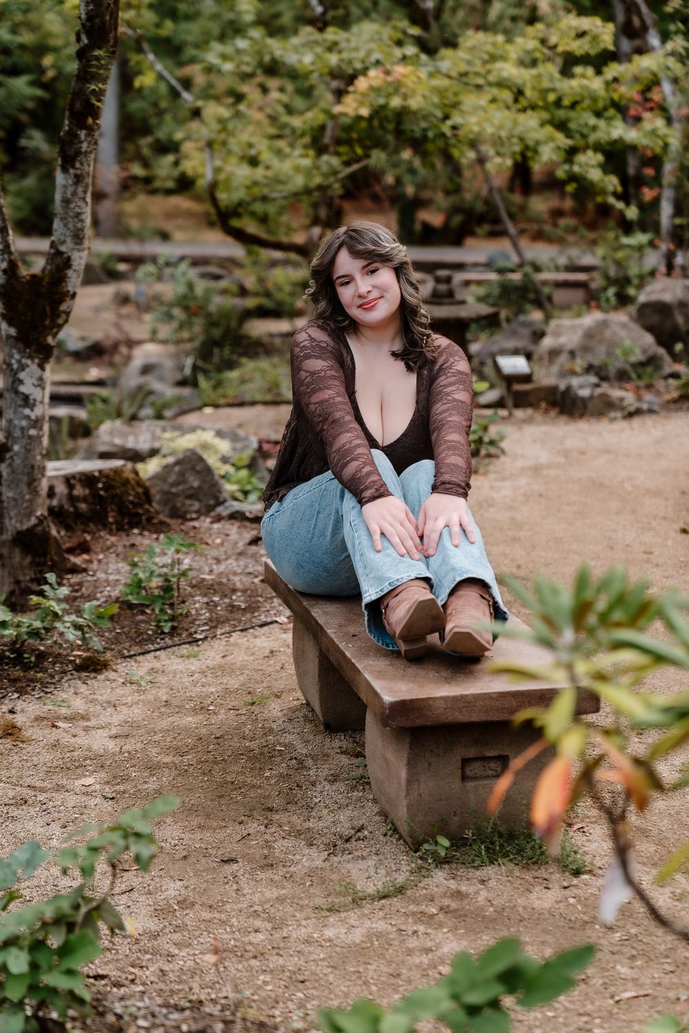 Casual outdoor portrait sitting on a wooden bench in a garden setting.