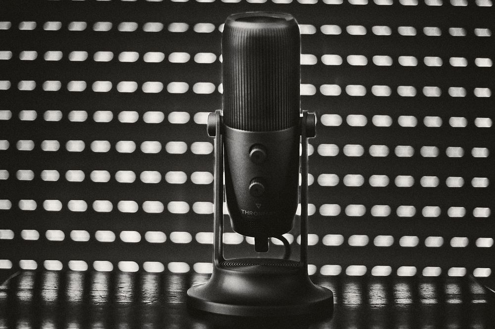 A close-up view of black studio microphones against a dotted light background creates a professional recording atmosphere.
