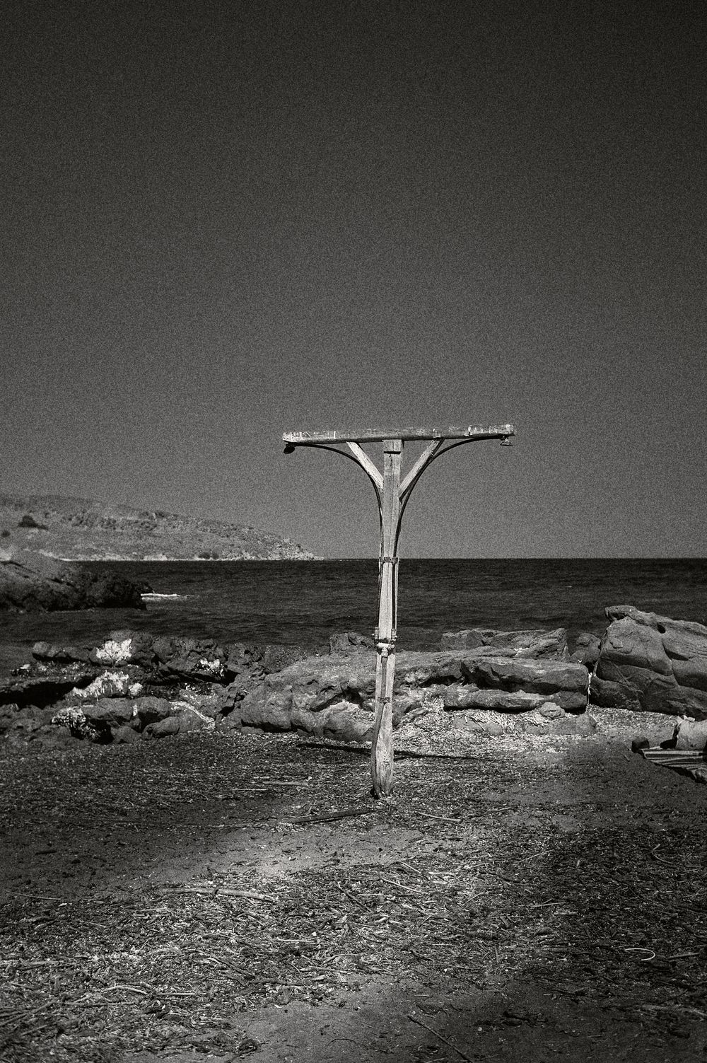 A series of black and white landscape photographs showing a solitary pole structure against a stark desert horizon.