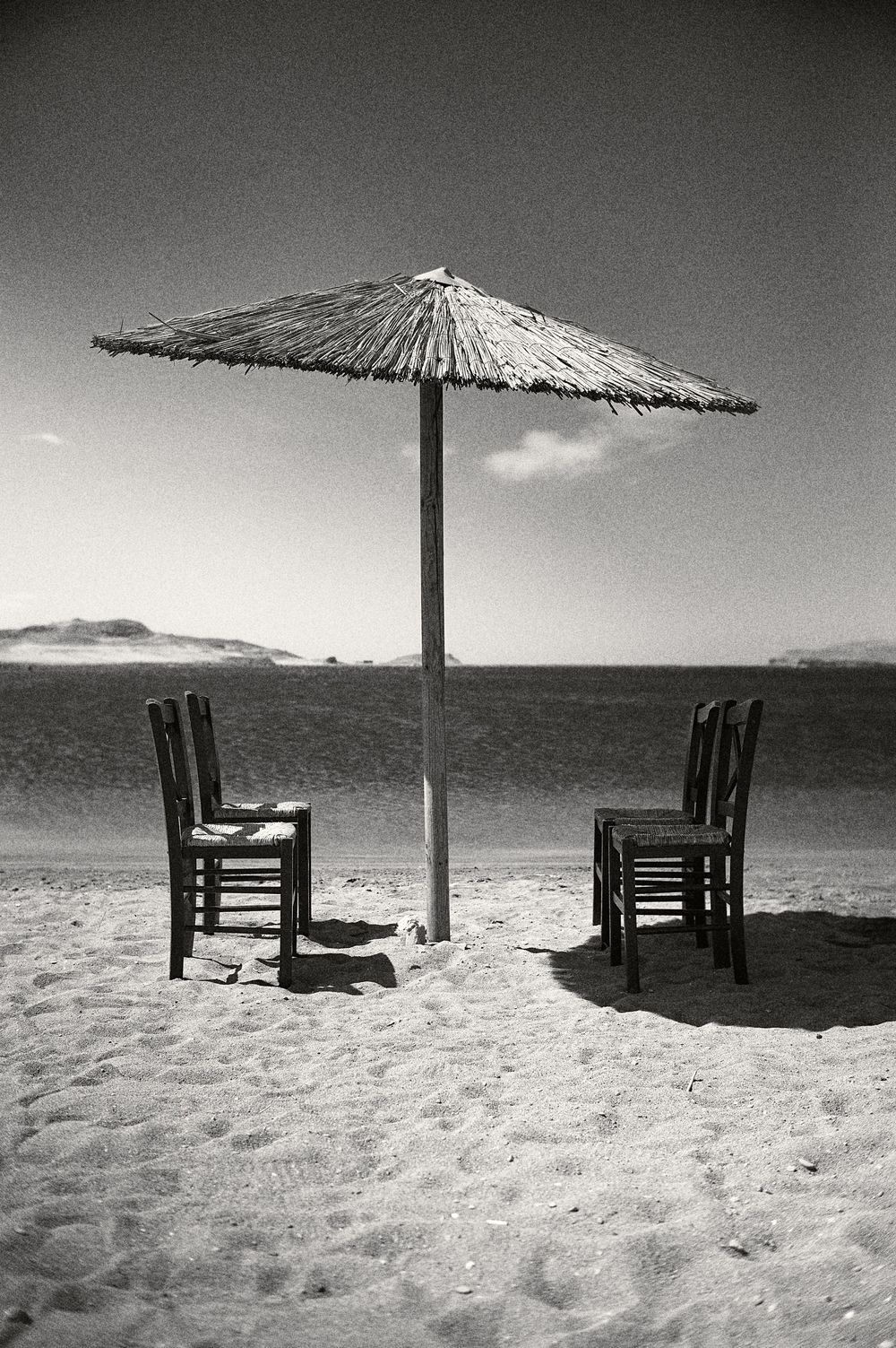 A series of black and white photos showing beach umbrellas and lounge chairs on an empty sandy shoreline.